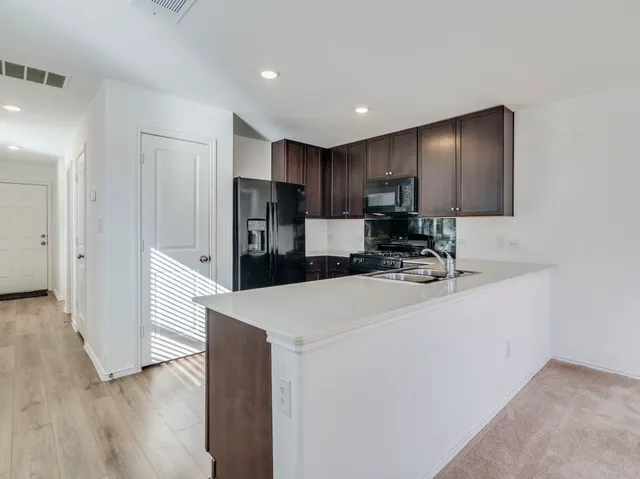 a kitchen with kitchen island a sink a stove a refrigerator and a refrigerator