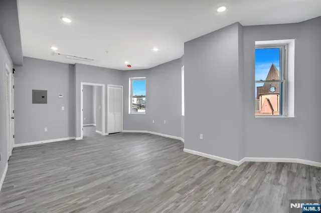 a view of an empty room with wooden floor and closet