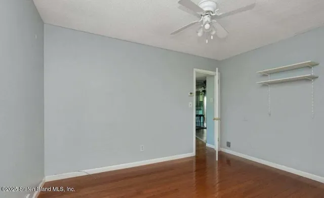 an empty room with wooden floor fan and window