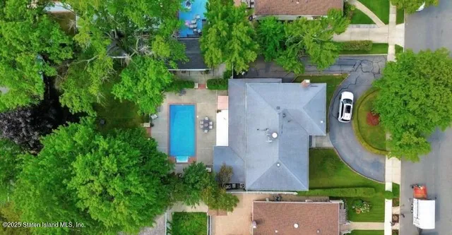 an aerial view of a house with a yard and trees all around