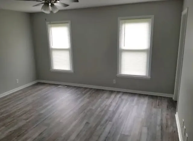 a view of an empty room with a window and wooden floor