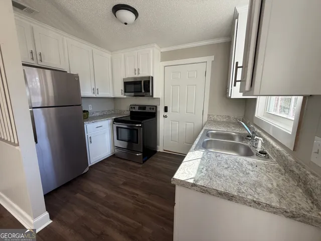 a kitchen with granite countertop a refrigerator stove and sink