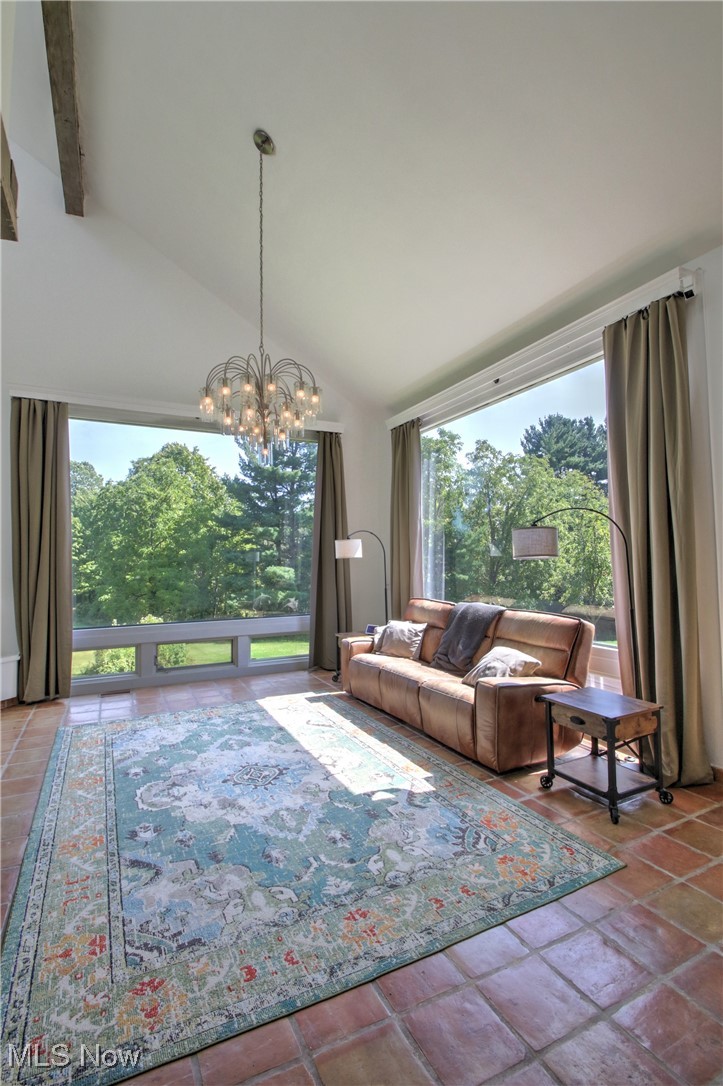 Living room with a chandelier, high vaulted ceiling, and beam ceiling