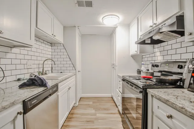 a kitchen with stainless steel appliances granite countertop a sink stove and cabinets