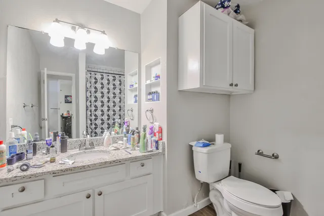 a bathroom with a granite countertop toilet sink mirror and vanity