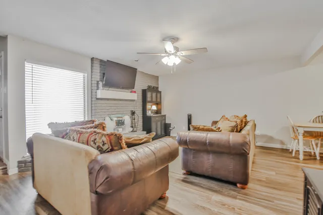 a living room with furniture a fireplace and a ceiling fan