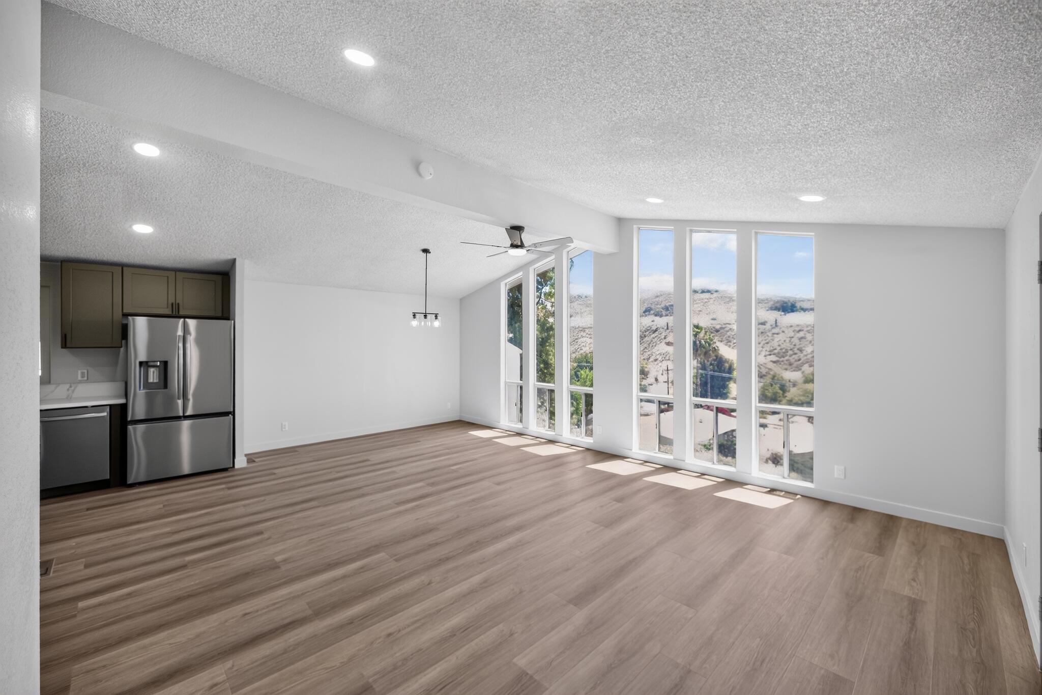 15181 Van Buren Boulevard, Unit 102 Riverside, CA 92504 - Photo 10 of 29 a view of an empty room with wooden floor and a kitchen
