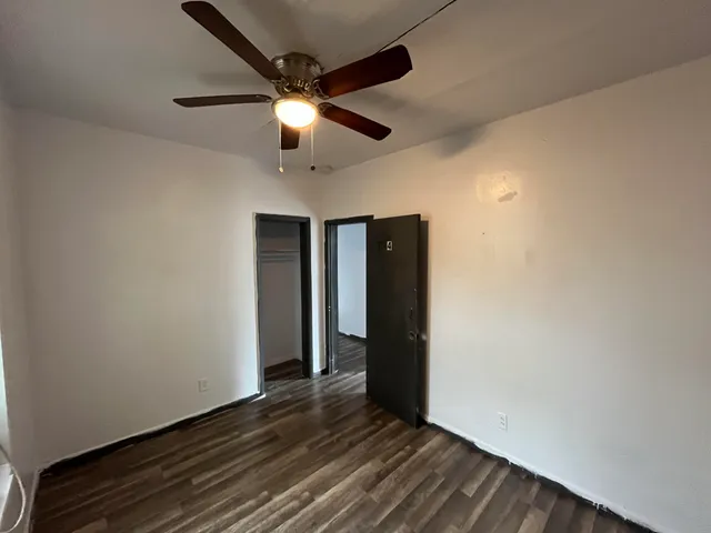 en empty room with wooden floor and ceiling fan