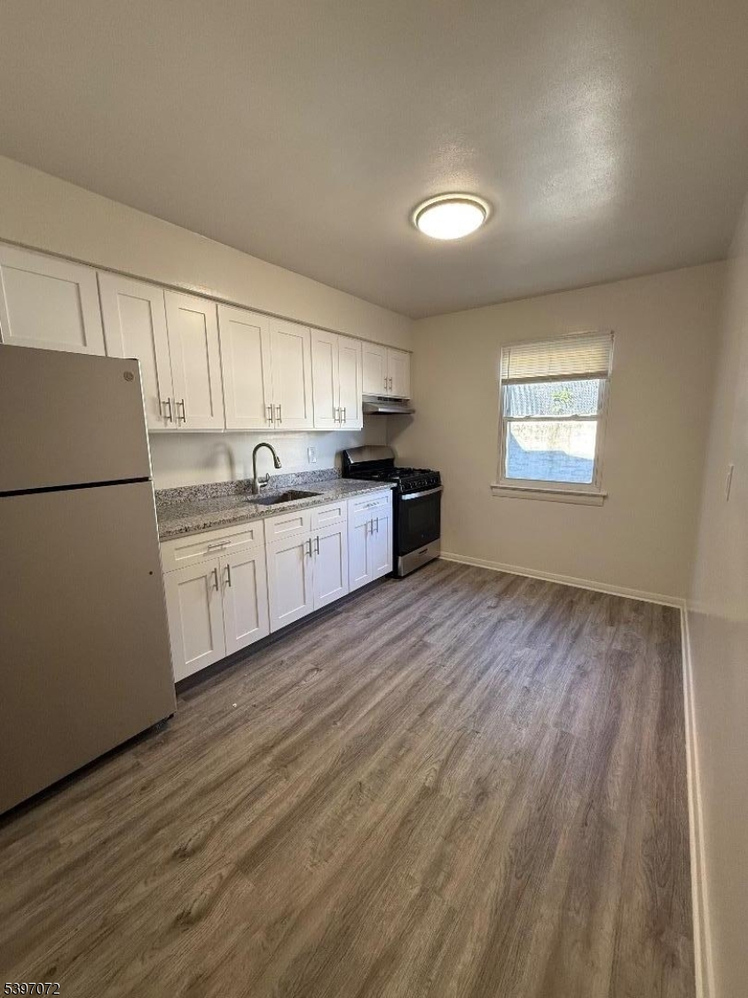 a kitchen with stainless steel appliances granite countertop a refrigerator a sink dishwasher a stove and white countertops with wooden floor