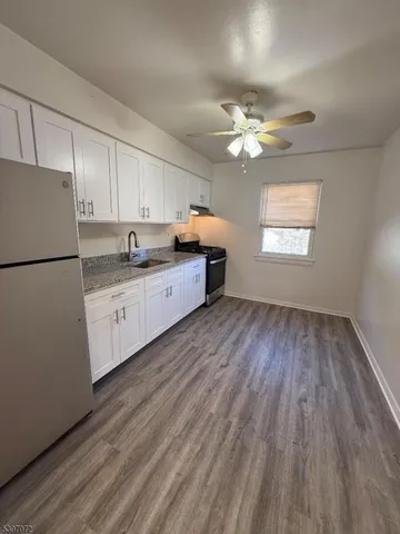a kitchen with cabinets wooden floor and a refrigerator