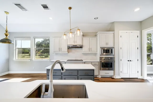 a kitchen with stainless steel appliances granite countertop a stove a sink and a refrigerator