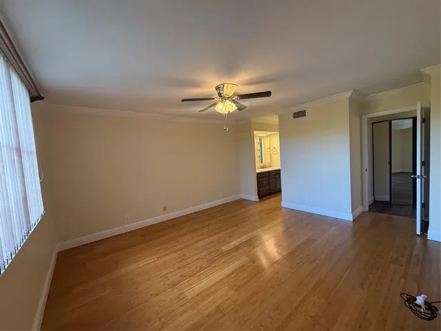 an empty room with wooden floor fan and windows