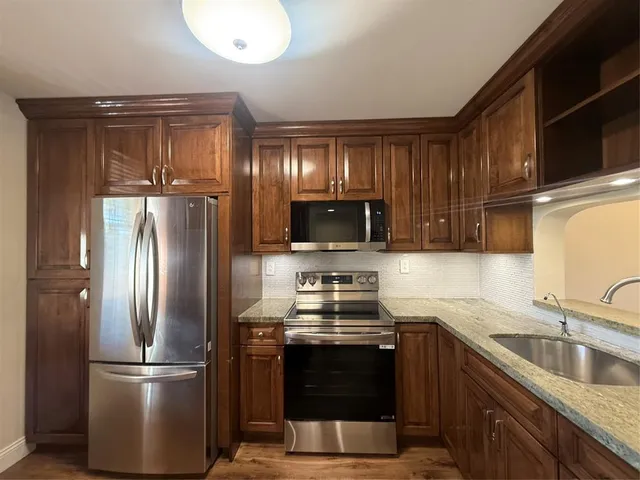 a kitchen with stainless steel appliances granite countertop wooden cabinets and a stove top oven