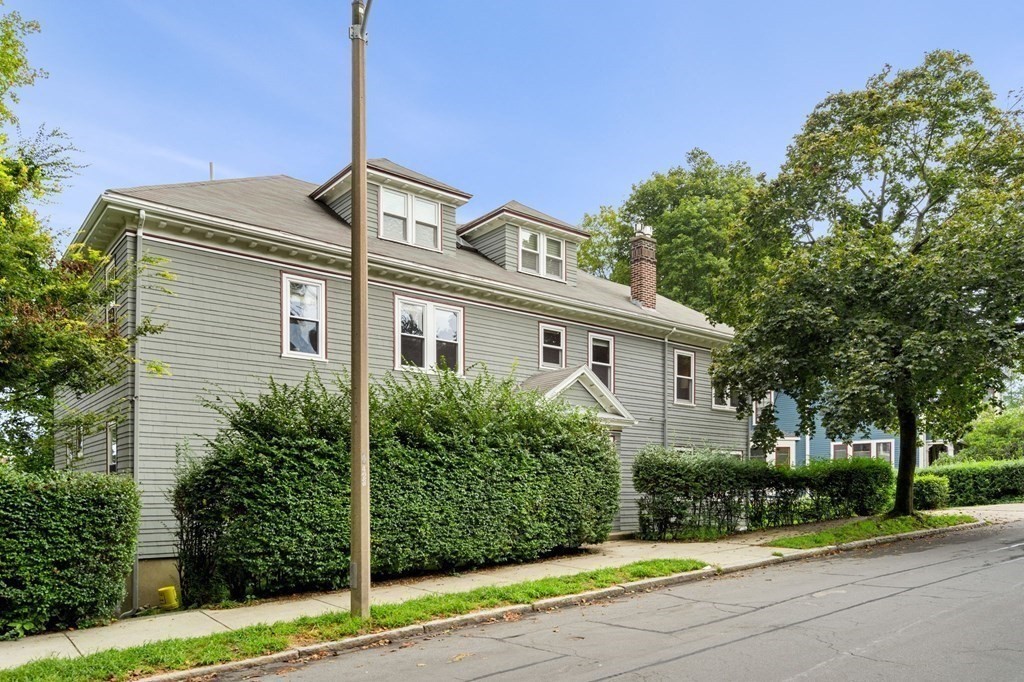 46 Gardner Road, Unit 2 Brookline, MA 02445 - Photo 38 of 38 a view of a white house with a large windows and a yard with plants and large trees
