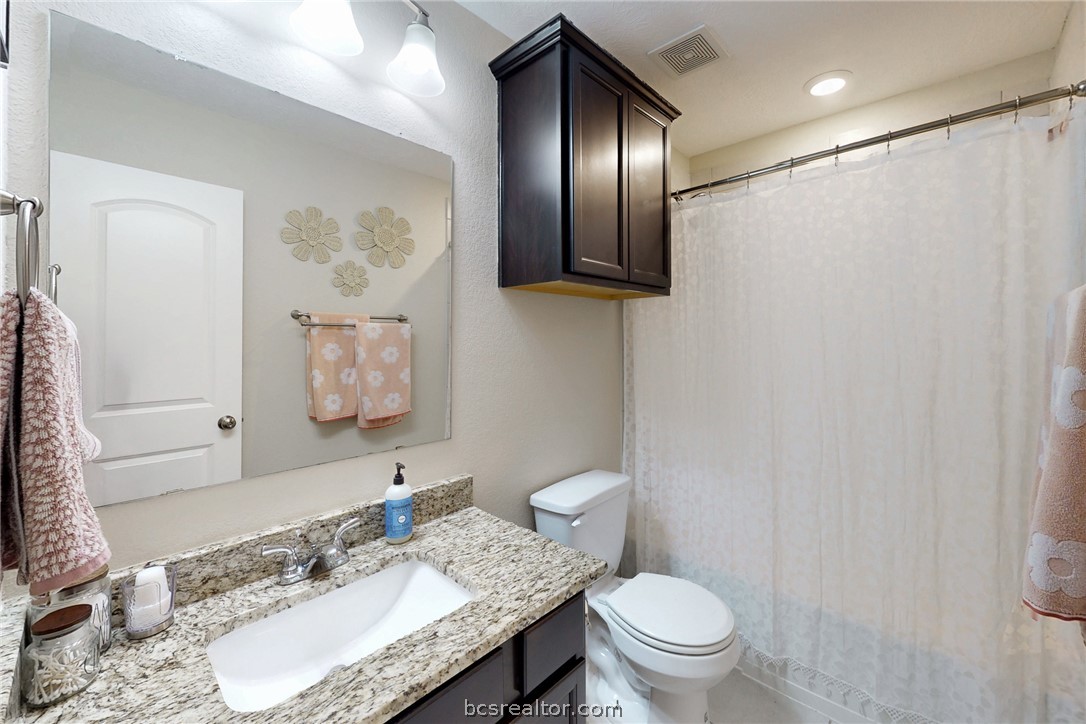 2071 Positano Loop Bryan, TX 77808 - Photo 21 of 31 a bathroom with a granite countertop sink mirror vanity and toilet