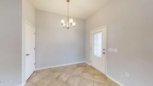 a view of empty room with chandelier and window