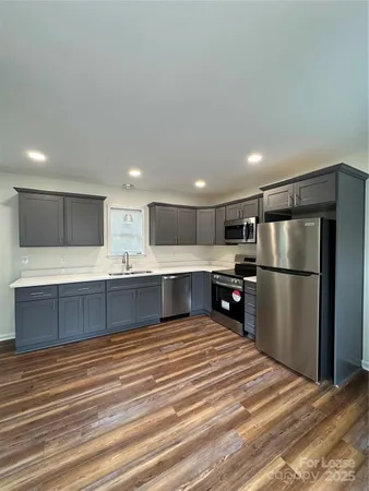 a large kitchen with stainless steel appliances kitchen island a large counter top and a refrigerator
