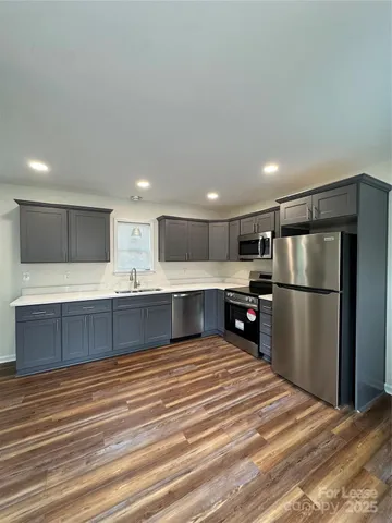 a large kitchen with stainless steel appliances kitchen island a large counter top and a refrigerator