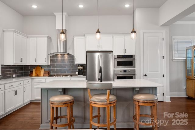 a kitchen with stainless steel appliances a table chairs in it and wooden floors