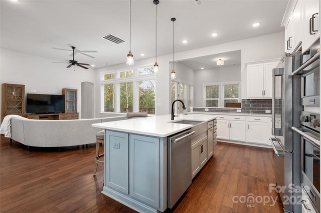 a kitchen with stainless steel appliances granite countertop a sink a stove and a wooden floor