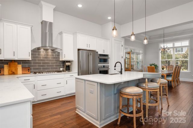 a kitchen with stainless steel appliances a dining table chairs stove and refrigerator