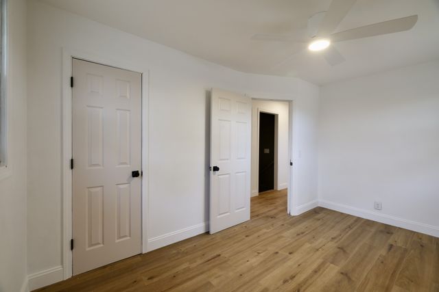a view of an empty room with wooden floor and closet