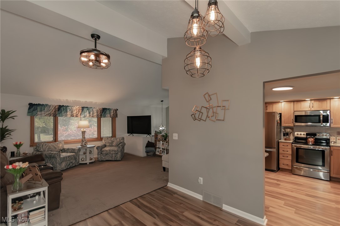 12745 Carter Road Painesville, OH 44077 - Photo 12 of 50 Living room featuring light wood-style flooring, a chandelier, beam ceiling, and high vaulted ceiling