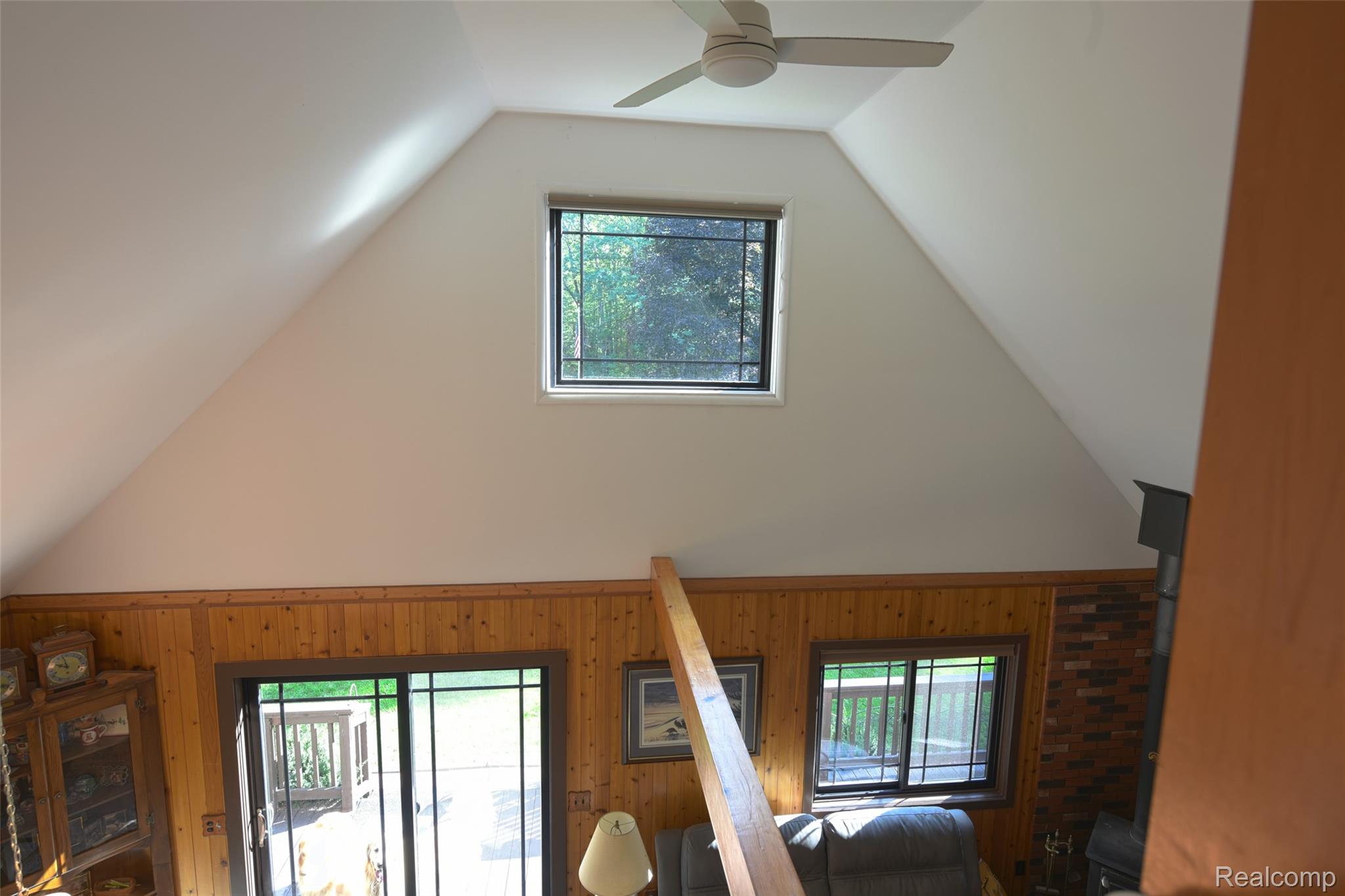 5799 Goodar Road South Branch, MI 48761 - Photo 27 of 58 Vaulted ceiling with a ceiling fan, upper window, wood paneling and sliding glass door leading to deck area