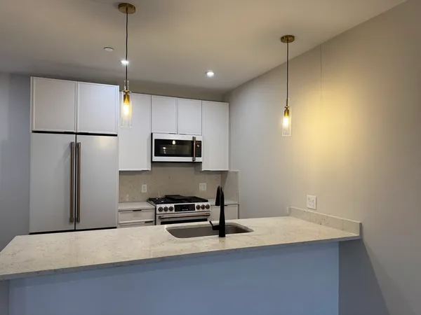 a kitchen with stainless steel appliances a refrigerator a sink a stove a microwave and island