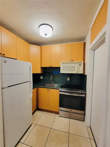 a kitchen with granite countertop a refrigerator and a sink