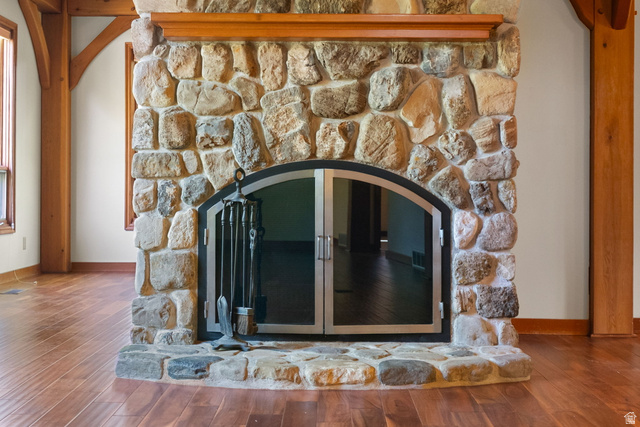 435 Canyon Road Millville, UT 84326 - Photo 10 of 113 Floor-to-ceiling stone fireplace with an arched glass door enclosure, a stone hearth, a wood mantel, and wood-finish flooring