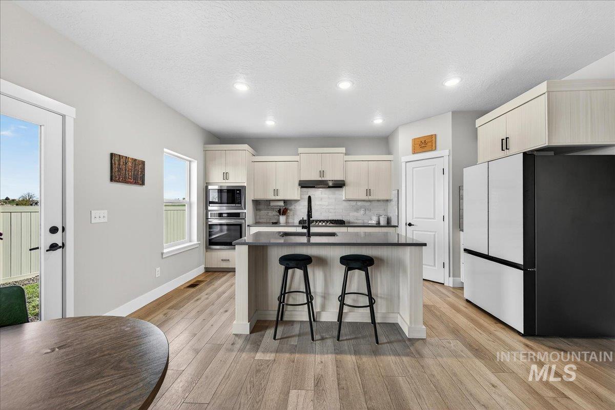 6025 South Catria Place Meridian, ID 83642 - Photo 11 of 34 Kitchen featuring stainless steel appliances, an island with sink, a breakfast bar, light wood finished floors, and recessed lighting