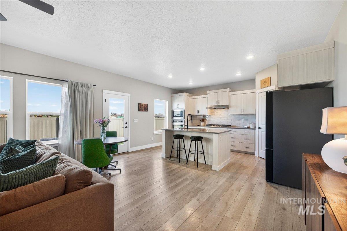 6025 South Catria Place Meridian, ID 83642 - Photo 34 of 34 Kitchen featuring stainless steel appliances, a kitchen bar, open floor plan, light wood finished floors, and a kitchen island with sink