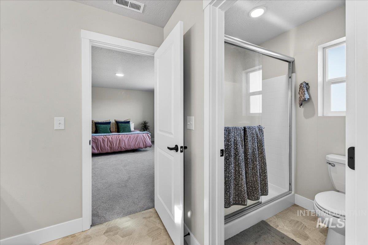 6025 South Catria Place Meridian, ID 83642 - Photo 20 of 34 Bathroom featuring a stall shower, light colored carpet, connected bathroom, and a textured ceiling