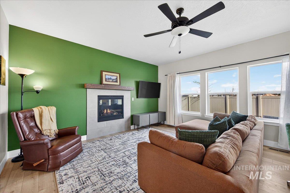 6025 South Catria Place Meridian, ID 83642 - Photo 4 of 34 Living room with light wood-type flooring, a tile fireplace, and a ceiling fan