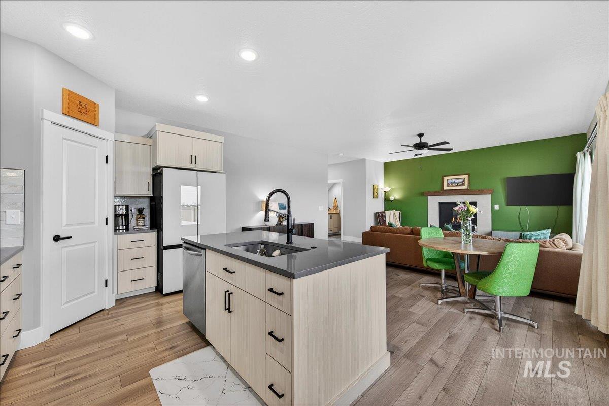 6025 South Catria Place Meridian, ID 83642 - Photo 33 of 34 Kitchen with cream cabinets, an island with sink, dark countertops, light wood-style flooring, and open floor plan