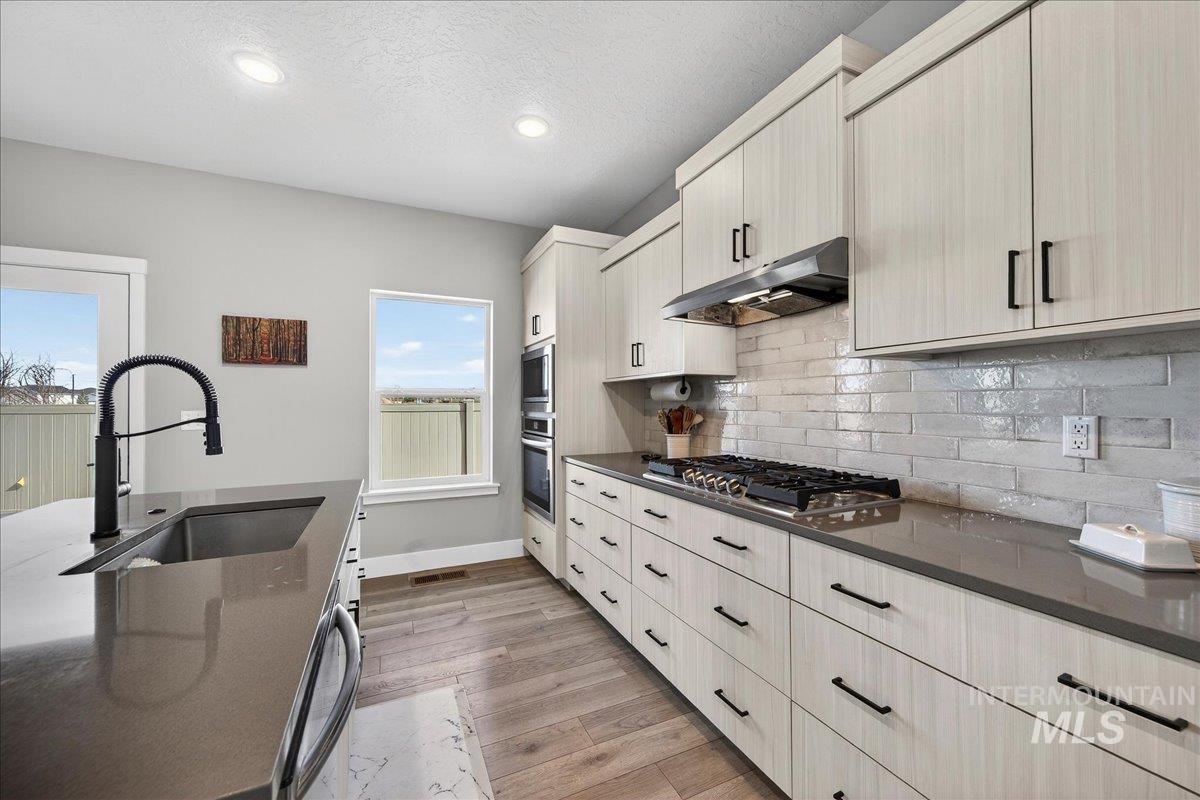 6025 South Catria Place Meridian, ID 83642 - Photo 8 of 34 Kitchen with light wood-style floors, dark stone countertops, recessed lighting, stainless steel appliances, and backsplash