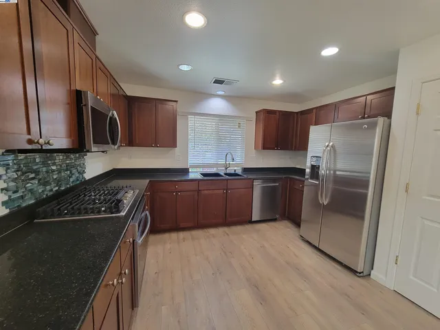 a kitchen with granite countertop stainless steel appliances and wooden cabinets