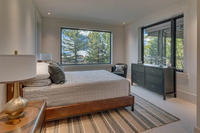 a bedroom with a bed and large windows