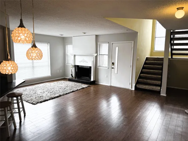 a view of an empty room with wooden floor and a fireplace