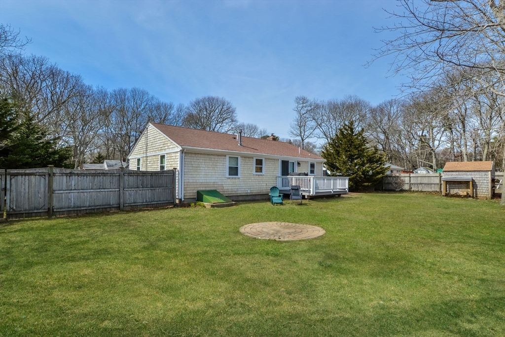 48 Kennedy Circle Barnstable, MA 02601 - Photo 4 of 32 a view of a white house in front of a big yard with large trees and wooden fence