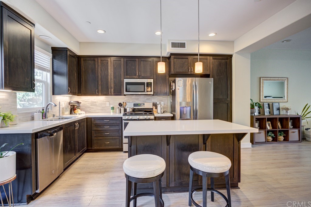 a kitchen with kitchen island granite countertop a sink cabinets and stainless steel appliances