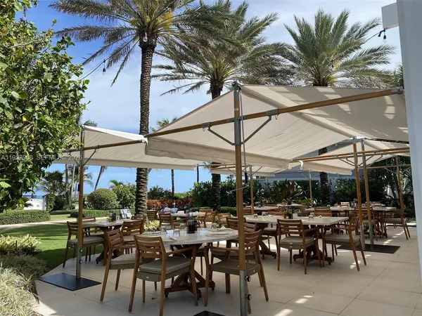 a view of a patio with table and chairs potted plants and a large tree