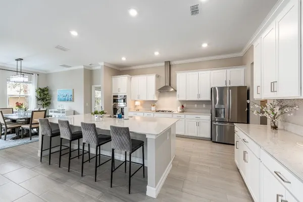 a large white kitchen with a stove a sink dishwasher and a dining table with wooden floor