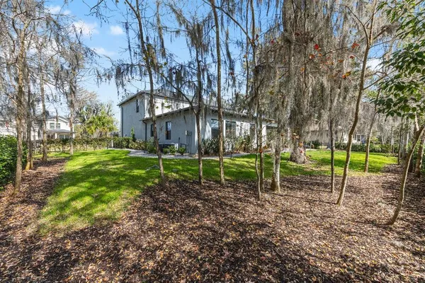 a view of a house with a yard fire pit and large trees