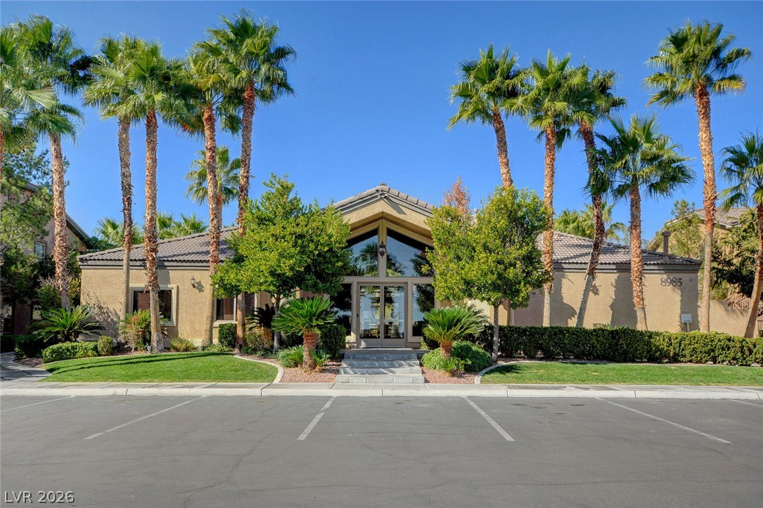 8985 South Durango Drive, Unit 2187 Las Vegas, NV 89113 - Photo 69 of 73 A well-maintained community building with an inviting entrance, lush landscaping, and mature palm trees.