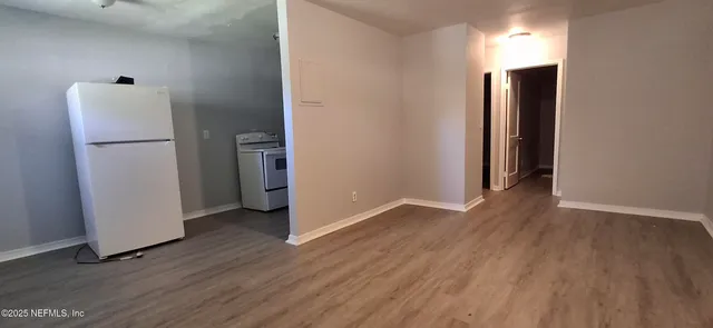 a view of a room with wooden floor and a hallway