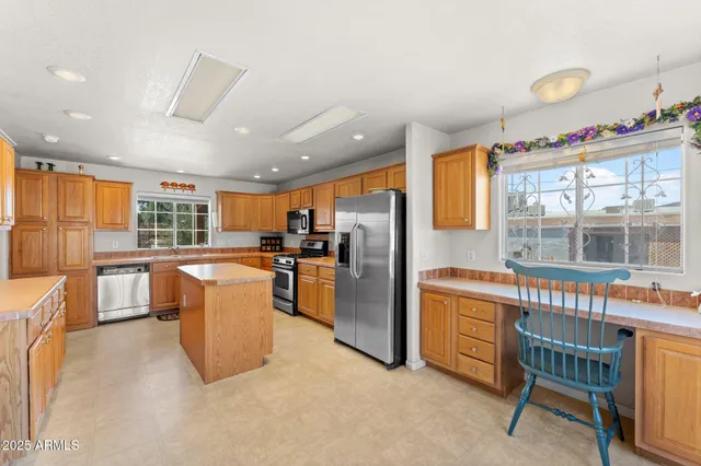 a kitchen with stainless steel appliances granite countertop a refrigerator a sink dishwasher a dining table and chairs with wooden floor