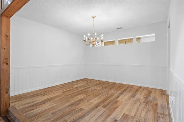 a view of a room with wooden floor and chandelier