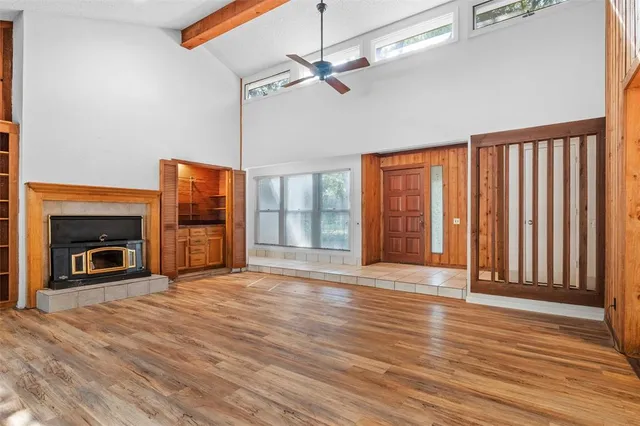 a view of an empty room with wooden floor fireplace and a window